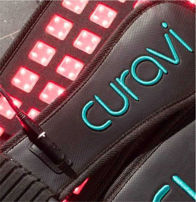 A Curavi Belt for pain management with the red laser lights on